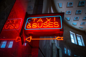 Bright vibrant red and blue city urban neon sign with arrow pointing to taxi and bus