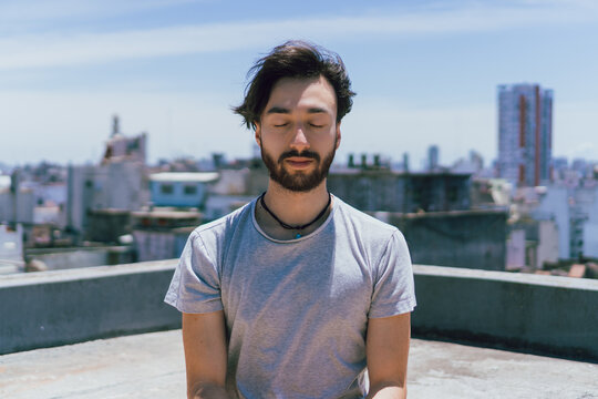 young latin man meditating on a terrace with eyes closed in the daytime, mindfulness transe meditation