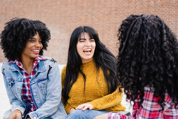 three young latina exchange students laughing together on the university campus - obrazy, fototapety, plakaty