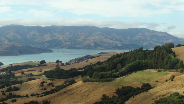 Tight parallax aerial revealing lake Akaroa bay surrounded by mountains and green hills breathtaking landscape