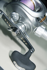 Unified in Silver color, saltwater fishing beit tackle reel and rod. Close up macro photograph.