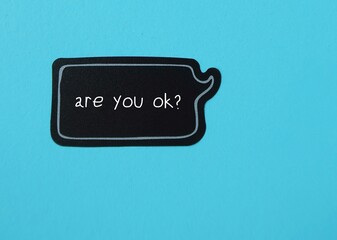Speech sticker on blue background with handwritten text ARE YOU OK?, to ask question to someone you...