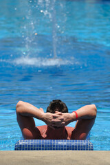 Man relaxing in a swimming pool full of a blue water, copy space