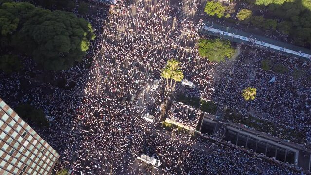 Multitude of people celebrating in 9th July Avenue around obelisk the final victory of soccer World Cup 2022, Buenos Aires. Aerial drone top-down view