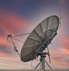 A satellite dish for use in telecommunication with a blue gold background at the end of the light.