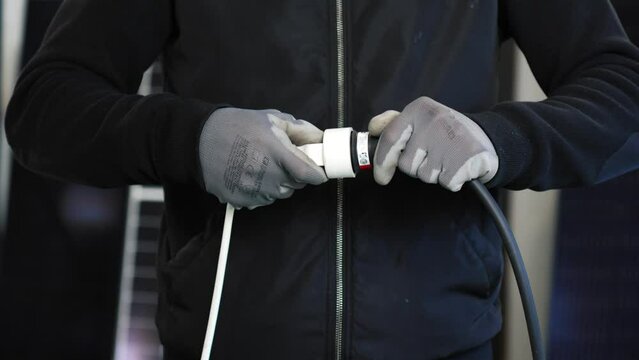 Electrician with gloves putting in the plug.