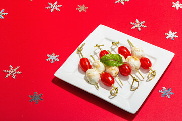 Traditional Italian appetizer in Christmas style. Mozzarella, cherry tomatoes on skewers. New Year
