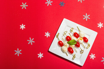 Traditional Italian appetizer in Christmas style. Mozzarella, cherry tomatoes on skewers. New Year