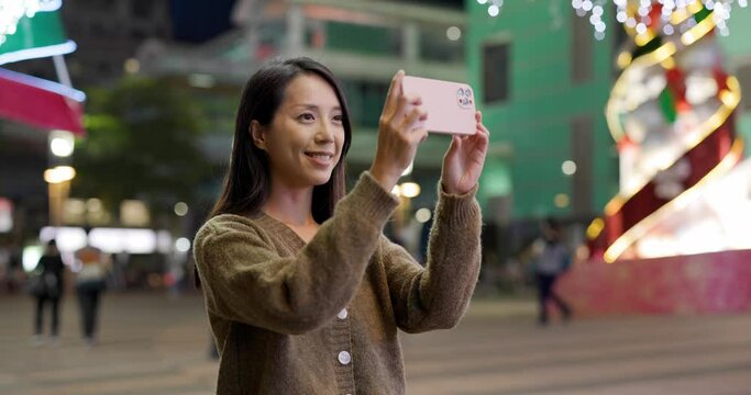 Woman take photo on cellphone in city at night