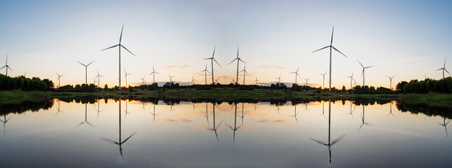 Powerful Wind turbine farm for pure energy production on Beautiful clear blue sky with white clouds and wind turbine farm reflection on lake. renewable energy	