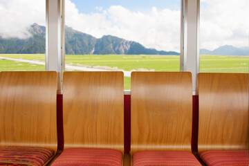 Train seats with wooden backrests and fabric seats
The seats are empty, with the scenery in the...