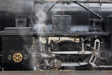 The steam locomotive is emitting smoke., close up