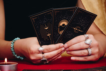 Tarot reader or Fortune teller of hands holding up black deck tarot cards. Tarot cards are spread...