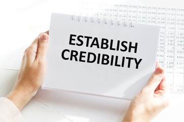 Closeup on businessman holding a card with text ESTABLISH CREDIBILITY, business concept image with soft focus background and vintage tone