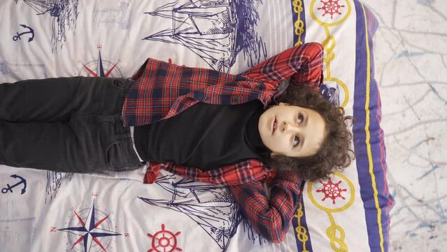 Curly haired boy using his imagination.
Boy lying on his bed dreams, imagining what will happen in the future.
