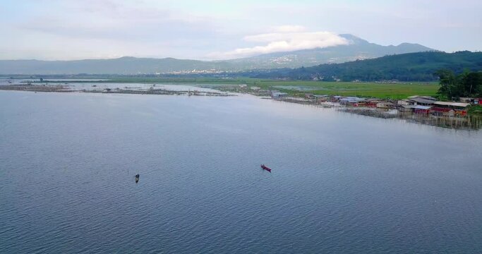 Aerial view of fisherman boat on the lake and fish cage on it. Lake with mountain background - Rawa Pening Lake, Indonesia