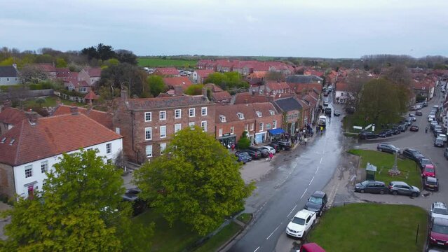 Aerial Drone Shot Flying Through Beautiful Old Village Burnham Market with People Walking in Street Shopping on Sunny and Cloudy Day North Norfolk UK