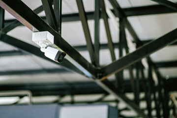 Close-up side view of a white CCTV security camera inside an industrial factory. closed circuit television CCTV electronic security system