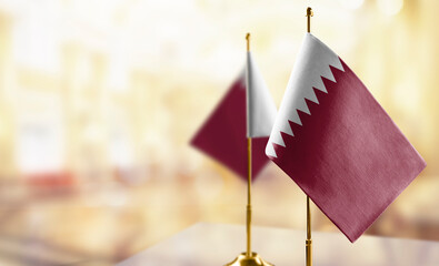Small flags of the Qatar on an abstract blurry background