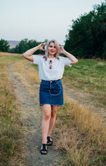 A sweet, young, happy, cheerful, pretty woman, walking outdoors in the park on a beautiful summer day. The girl listens to music with headphones.