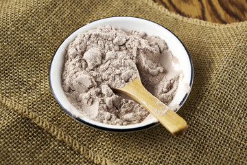 Black salt Kala namak in a salt shaker with a wooden spoon on a burlap