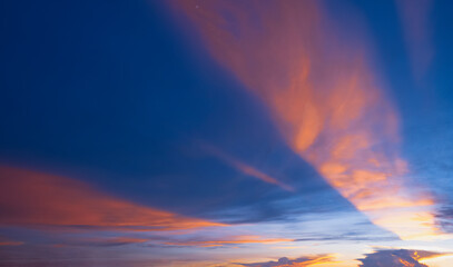 Dramatic dusk sky background in the evening with majestic orange sunlight on dark blue clouds after sundown