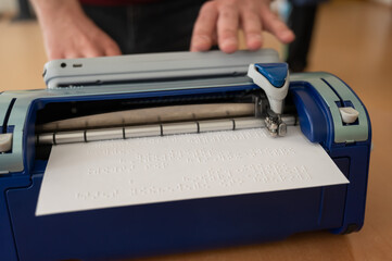 Blind man using braille typewriter. 