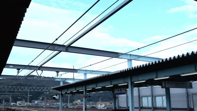Scenic regional train station empty platform with overhead electrical lines in Japan.