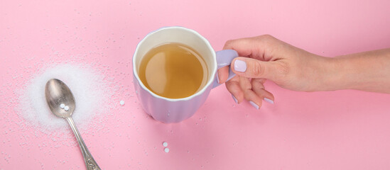 Cup of tea with sugar substitute on pink background.