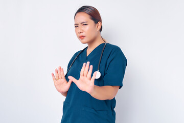 Angry young Asian woman nurse wearing blue uniform with a stethoscope frowning displeased, extend...