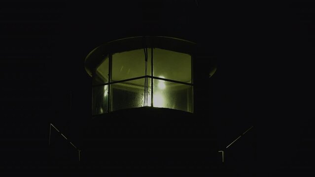 Lighthouse burning at dusk. Lighthouse light in rainy weather. Rotating lighthouse.