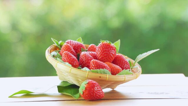 Red strawberry in wooden basket on blurred greenery background, Red Korean Strawberries on wooden table in garden.