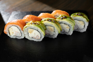 Philadelphia roll sushi with salmon, prawn, avocado, cream cheese on black stone. Sushi menu. Japanese food.