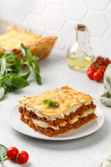 Delicious Lasagne with bolognese meat sauce and cheese on white plate and grey background. Traditional Italian lasagna.