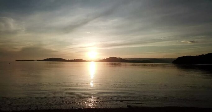 Camera moves along tropical island surf strip at sunset.Bright sunrise over the sea and islands ,Lombok, Indonesia, south Gili islands.Dolly shot.