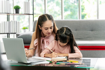 Asian family portrait, father and daughter in the living room The daughter did her homework with her mother, giving advice and teaching closely.
