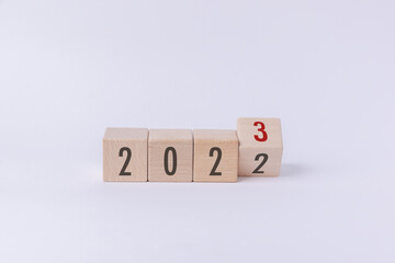 Flipping wood cube block from 2022 to 2023 text isolated in white background. New year goal, action plan, business plan, finance and marketing strategy concept.