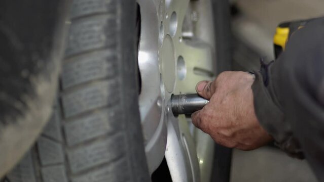 Mechanic fixing, changing tire in car service shop center. Transport maintenance detail.