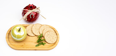 Fototapeta na wymiar Pomegranate, green apple and round bread on wooden tray on white festive background for Rosh Hashanah