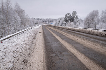 clean wet asphalt road in wintertime. Dirty snow on road sides. Long far perspective. Latvia...