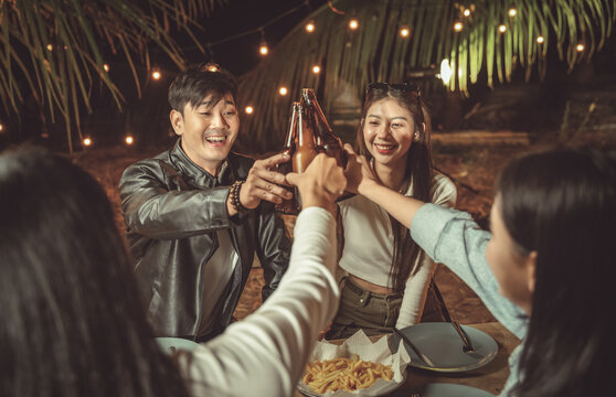 Friends toasting with beer at rustic dinner party
