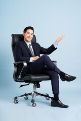 Asian businessman male portrait sitting on chair and isolated on blue background