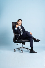 Asian businessman male portrait sitting on chair and isolated on blue background
