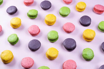 background of sweet macaroon cookies in different colors on a pink background