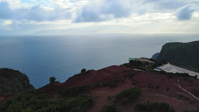 Aerial view of stunning viewpoint Mirador de Abrante with glass observation balcony above Agulo village in La Gomera island at sunrise. Restaurant on red clay.