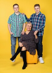 A family. Studio. two guys and a woman pose for the camera. adult children and mother. yellow background