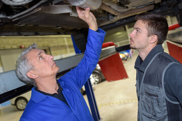 mechanic and apprentice working on car together