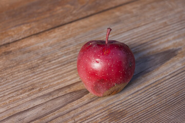 A red apple lies on a wooden surface