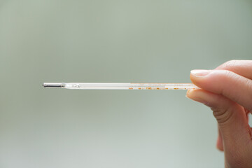 Hand with thermometer background. Temperature or fever measuring by thermometer.