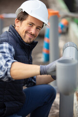 tradesman fixing sewerage pipe at construction site - obrazy, fototapety, plakaty
